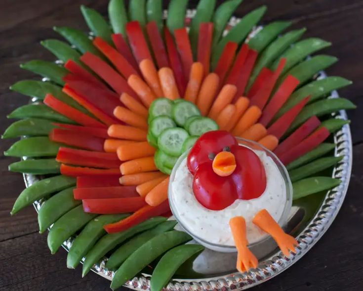 a platter with carrots, celery, cucumbers and dip