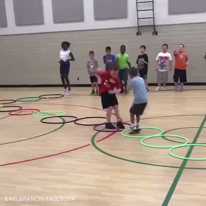 several young boys are playing frisbee in an indoor gym while adults watch from the sidelines