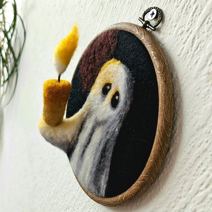 a needle - embroidered picture of a ghost with a candle in its hand is hanging on the wall