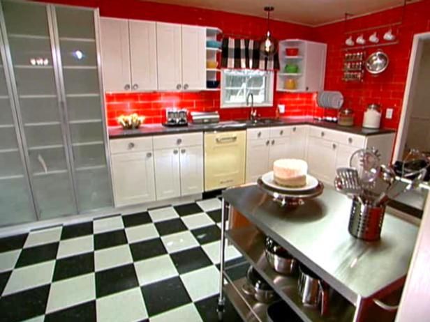 a kitchen with black and white checkered flooring, red walls, and stainless steel appliances