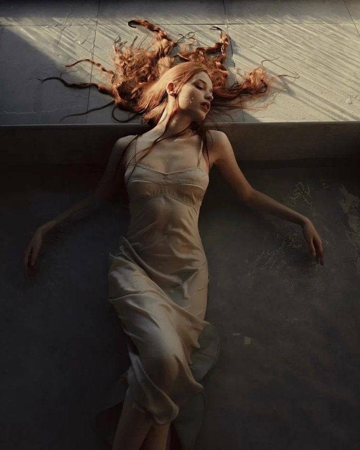 a woman laying down on the ground with her hair blowing in the wind as if she was falling asleep