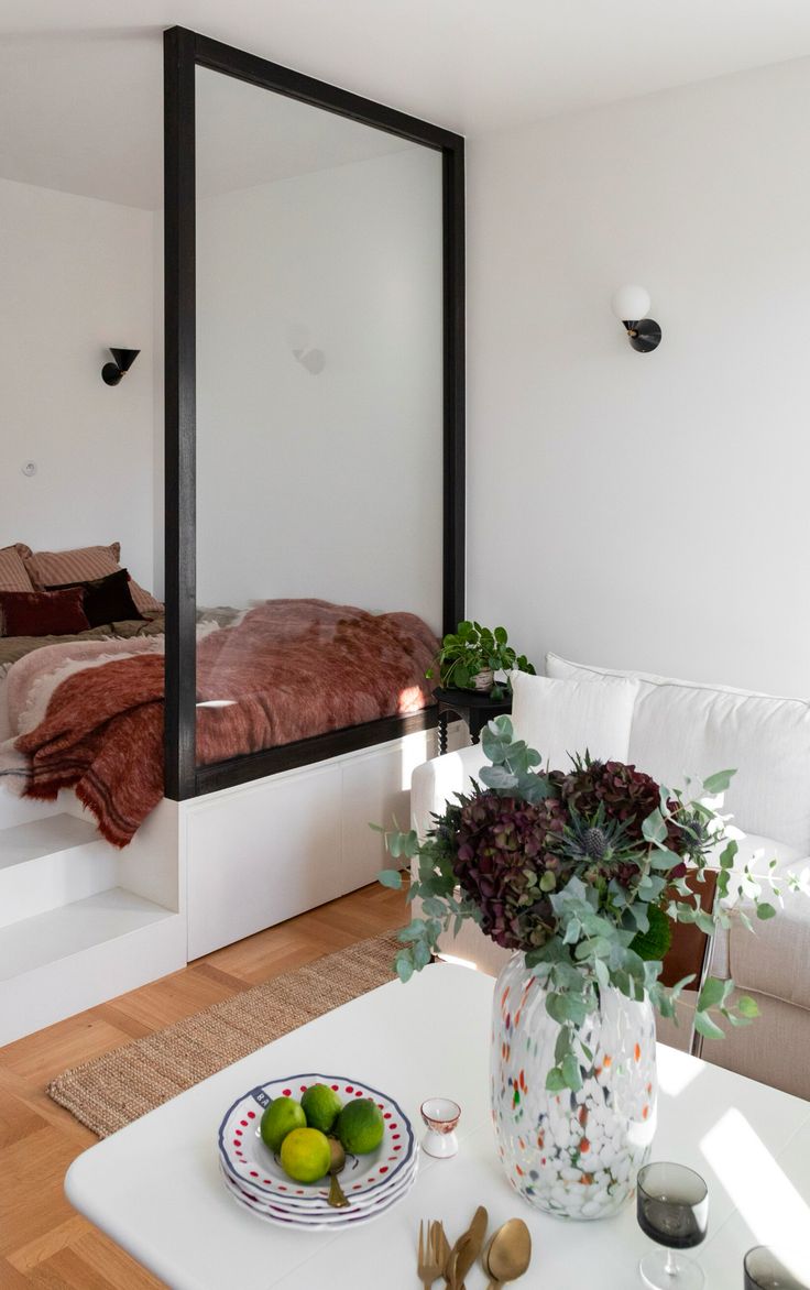 a living room with white furniture and a large mirror on the wall above it's bed