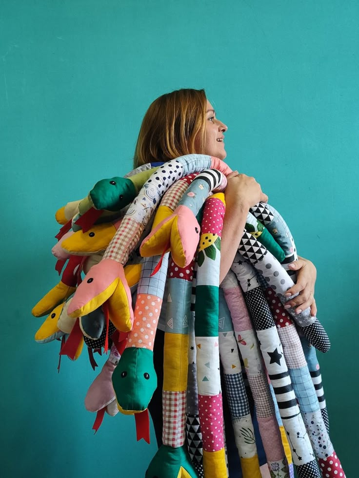 a woman holding a bunch of stuffed animals in front of a blue wall with green walls