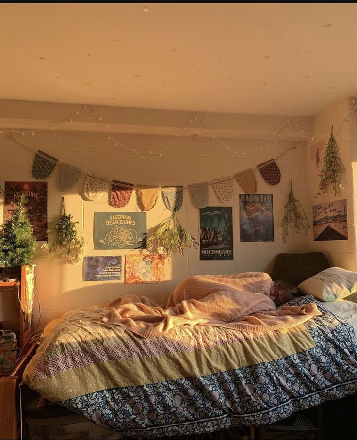 an unmade bed sitting in a bedroom next to a wall with pictures on it