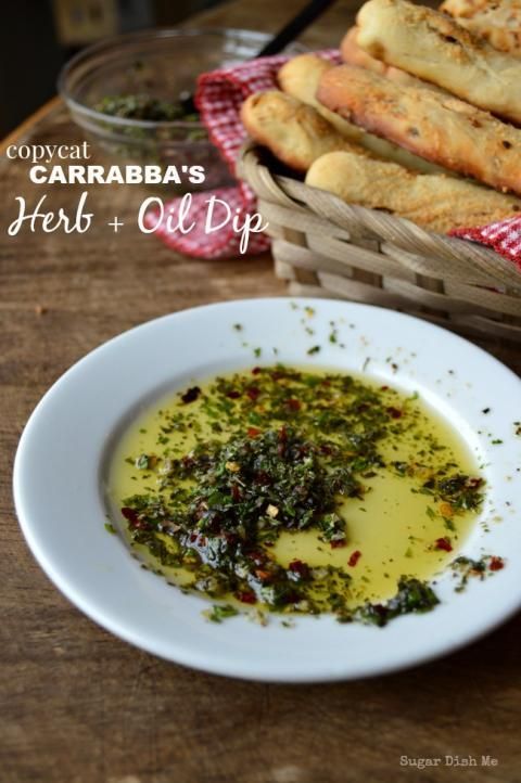 some bread sticks are on a table next to a bowl of pesto and oil