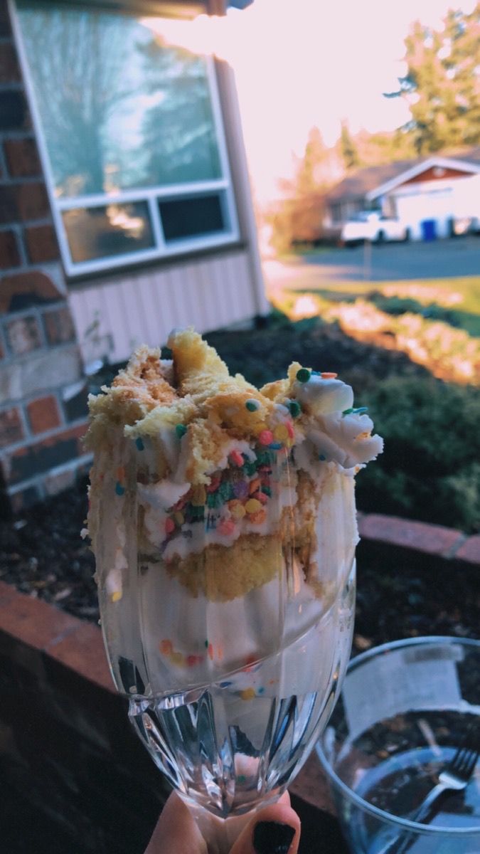 someone is holding up a glass with ice cream and sprinkles on it