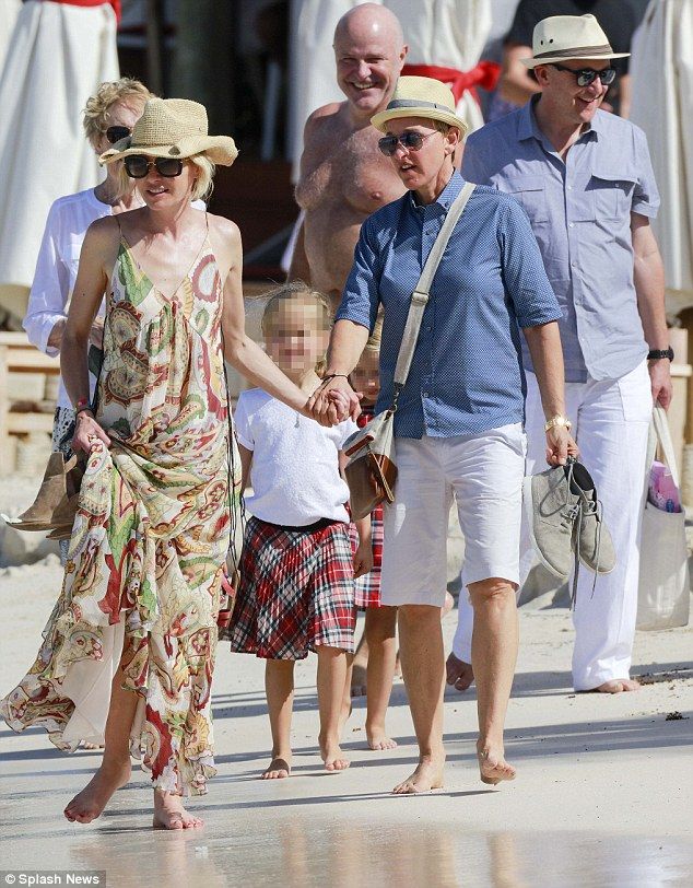 a group of people walking on the beach with one woman in a dress and two men in hats