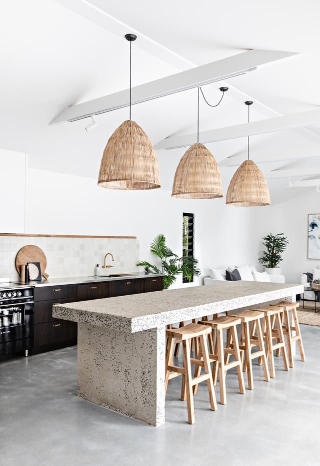 an island with stools in the middle of a room and lights hanging from the ceiling