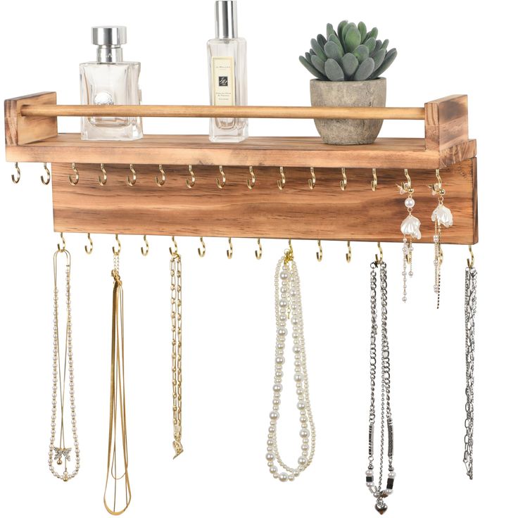 a wooden shelf with jewelry hanging from it's sides and a potted plant on top