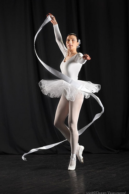 a young ballerina in white is posing for the camera