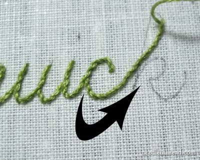 the word stitched on top of a piece of fabric with an arrow pointing to it