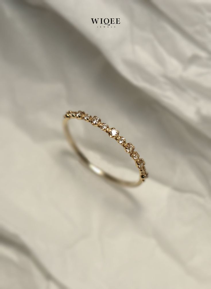 a gold ring with small stones on it's side, sitting on a white sheet