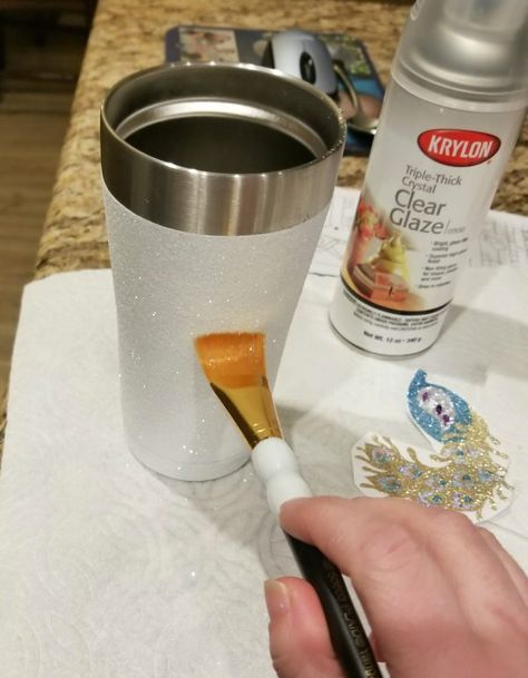 someone using a brush to paint the inside of a cup with gold flecks