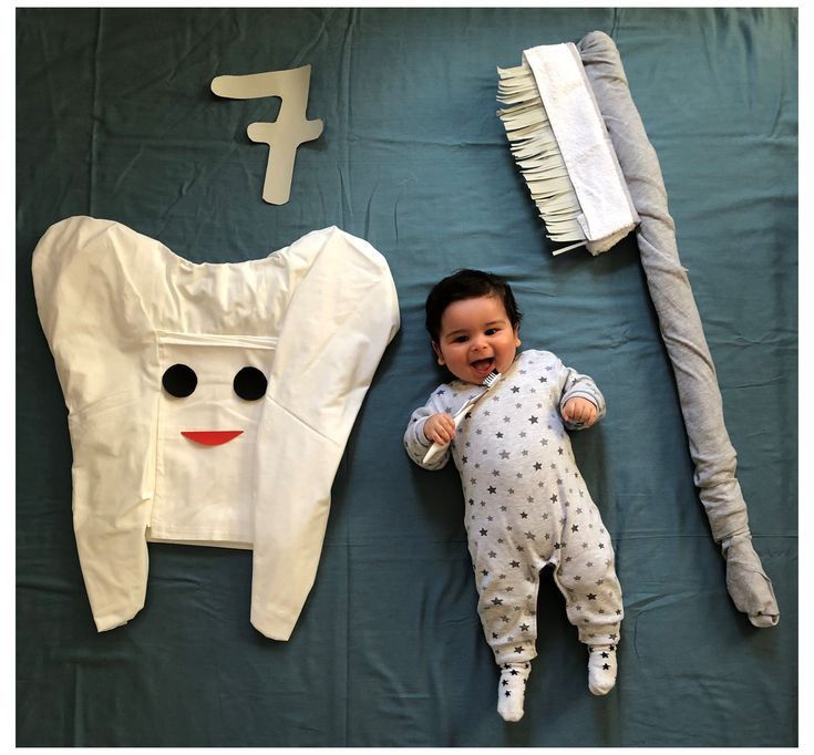 a baby laying on top of a bed next to a toothbrush and other items