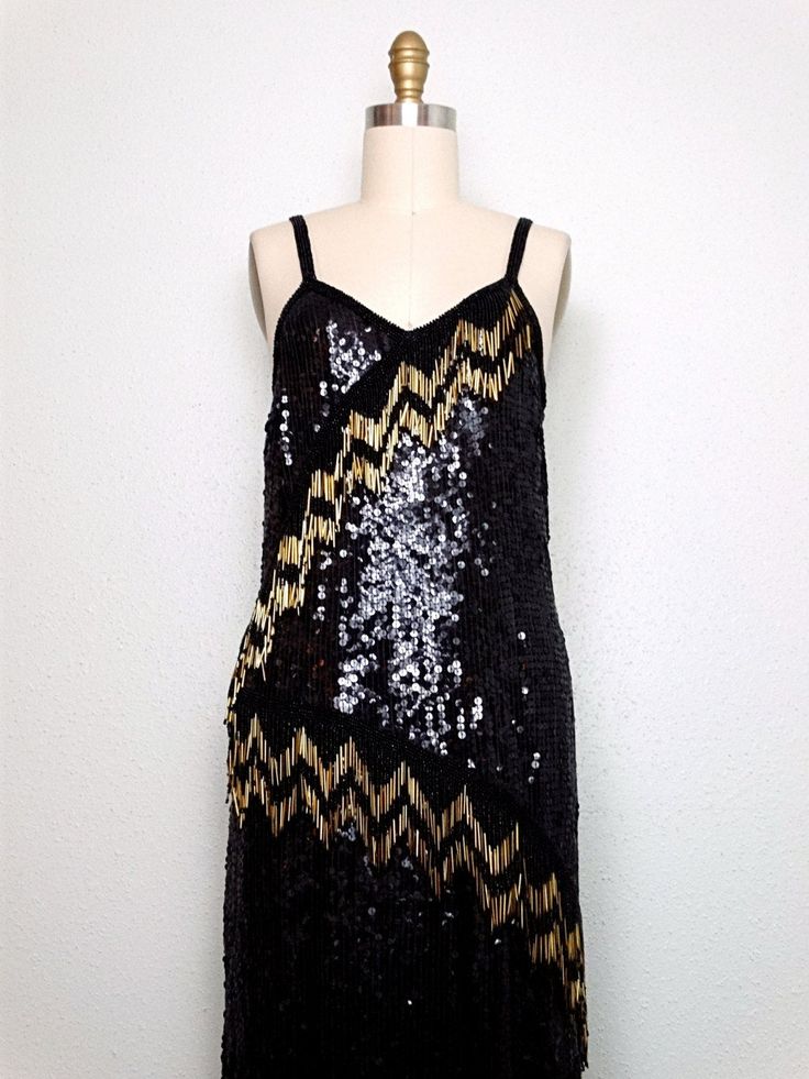 "This is a gorgeous vintage hand beaded dress fully embellished with black sequins and beads and accented with long gold glass beading in 4\" strands in an asymmetrical design. It jingles with movement ... STUNNING!! It's in excellent condition. Bust - 36/38\" Waist - 36/38\" Hips - 38/40\" Length - 34-49\" Tag Size - Large This dress comes from a pet-free and smoke-free home. If you would like more info or have any questions, please don't hesitate to ask!" Sequin Gatsby Dress For Costume Party, Gatsby Style Sequined Dress For Costume Party, Festive Gatsby Style Sequin Dress, Vintage Sequined Flapper Dress For Party Season, Glamorous Black Sequined Flapper Dress, Holiday Sequin Flapper Dress For Costume Party, Gatsby Style Embellished Sequin Cocktail Dress, Holiday Sleeveless Flapper Dress With Sequins, Gatsby Style Sequin Party Dress