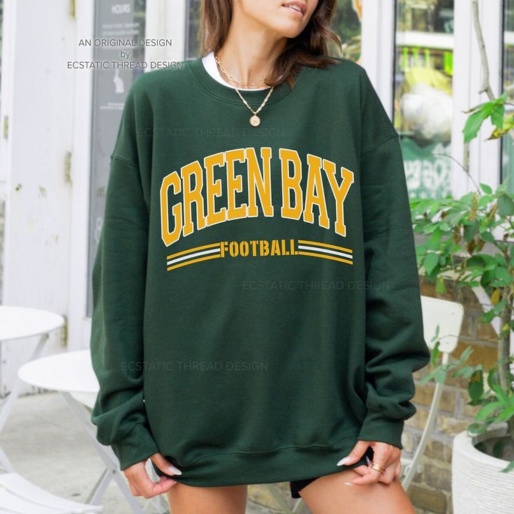 "Get ready for Green Bay football with this vintage-style, varsity sweatshirt. This crewneck has a retro design for your game day.  - These are Unisex fit. Please check sizing if you would like to order up 1-2 sizes for an oversized sweatshirt. * Packaged and Shipped in the USA! ---UNISEX SWEATSHIRTS--- - Specially spun cotton/poly, 50/50 - Medium-heavy soft fabric - Classic fit - Tear-away label - Runs true to size ---SIZES--- Small - 20\" W | 27\" L Medium - 22\" W | 28\" L Large - 24\" W | 29\" L XLarge - 26\" W | 30\" L 2XLarge - 28\" W | 31\" L 3XLarge - 30\" W | 32\" L 4XLarge - 32\" W | 33\" L ---CARE INSTRUCTIONS--- - Wash clothing inside out on cold setting - Tumble dry: low heat setting - Do not use bleach - Do not dry clean - Do not iron directly on design - Colors may look slig Long Sleeve Top With Team Name For Fall, Winter College Sweater With School Spirit, Collegiate Green Sweatshirt For Football Season, Green Collegiate Sweatshirt For Sports Season, Collegiate Sweater For Game Day In Fall, Varsity Sweater For Game Day In Winter, Crew Neck T-shirt For Game Day In Fall, Team-colored Tops For Sports Events In Fall, Collegiate Fall Sweater For Game Day