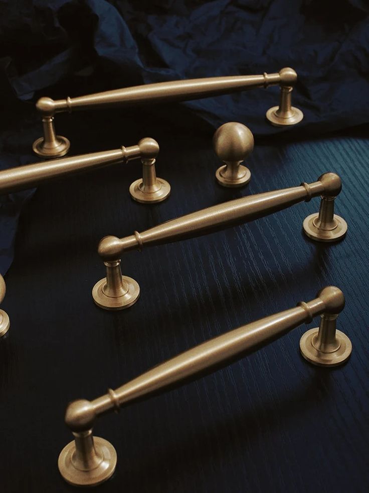 an assortment of brass handles and knobs on a black surface with a blue background