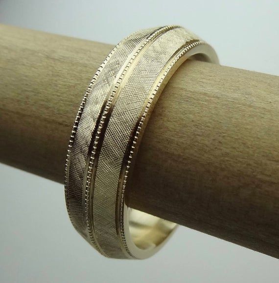 This bevel-edge  band is hand Florentine  all-round  approximately 6.5mm wide and weight is  approximately  10 to 11 grams of 14k yellow gold. The band is milgrain in the center and sides. Available in all finger sizes from 8 - 12.  Sizing outside of that range is a special order, contact for pricing and info.Each band is made to order and is a final sale.  If you need the band sooner than the listed processing time, we may able to do a rush order if our workload permits.We love this ring becaus Luxury 14k Gold Jewelry With Decorative Band, Fine Jewelry Wedding Rings With Milgrain Detail, Yellow Gold Oval Jewelry With Decorative Band, Elegant Thick Band Wedding Ring, Oval Yellow Gold Jewelry With Decorative Band, Decorative Oval Yellow Gold Jewelry, Engraved Yellow Gold Bands For Formal Occasions, Round Engraved Bands For Marriage, Classic Jewelry Ring With Decorative Band