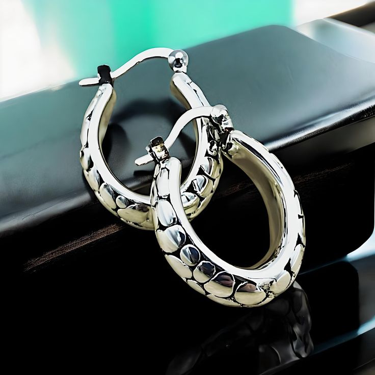 Elevate your jewelry collection with our exquisite Lightweight Oval Cobblestone Design Hoop Earrings, meticulously crafted from premium 925 Sterling Silver. Each earring boasts a delicate hollow construction, ensuring both comfort and elegance. The dimensions of these sophisticated hoops are approximately 18.5 mm in width and 21.4 mm in length, offering a striking presence without overwhelming. They are subtly stamped with '925' to certify their sterling silver composition. Experience the perfec Luxury Silver Tarnish-resistant Huggie Earrings, Silver Huggie Earrings In Fine Jewelry Style, Silver Tarnish Resistant Huggie Earrings For Formal Occasions, White Gold Oval Huggie Earrings For Gift, Silver Oval Huggie Earrings For Gift, Silver Oval Huggie Earrings As A Gift, Oval Sterling Silver Huggie Earrings For Gift, Silver Oval Tarnish Resistant Hoop Earrings, Oval Sterling Silver Huggie Earrings As Gift