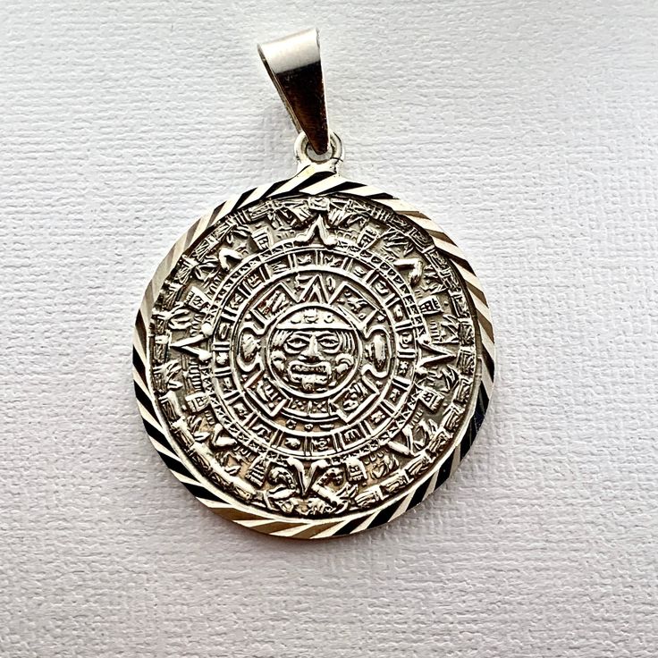 Silver Ancient Aztec Mayan Sun Calendar Diamond Cut Pendant. Exquisitely crafted in genuine 950 sterling silver with dazzling cut details. Pendant Height: 1.8 Inches Silver Pendant With Diamond Cut, Silver Pendant Jewelry With Diamond Cut, Silver Diamond Cut Pendant Jewelry, Luxury Silver Medallion Jewelry, Sterling Silver Medallion With Diamond Cut, Sterling Silver Jewelry With Diamond Cut In Silver, Symbolic Engraved White Gold Jewelry, Etched Medallion Jewelry In White Gold, Silver Diamond Cut Round Pendant Jewelry