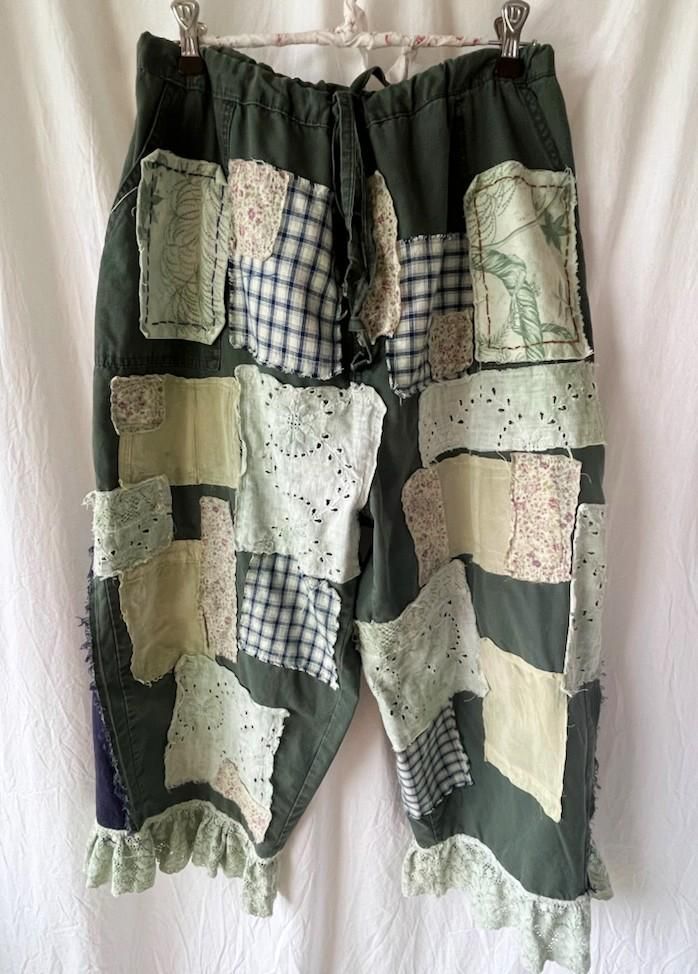 These plus-sized upcycled green cotton pants are decorated with an abundance of patches such as floral, checked cotton, silk, denim, botanical, and lace. The lace and patches have been dyed a very light green with natural plant dye. They are a women's size 18. The legs are flared starting about 11 inches from the waistband. There is some hand stitching included on the front pockets. There is extensive fraying on all of the patches and the triangle inserts on the sides of the pant legs. Here are the measurements for the upcycled pants: waistband-40 inches length-35 inches inseam-22 inches thigh circumference-30 inches hem circumference- 25 inches bottom lace circumference- 38 inches There are two buttons for an adjustable fit. When the drawstring is cinched and the second button is buttoned Upcycled Pants, Green Cotton Pants, Denim Patchwork Jeans, Patchwork Pants, Patchwork Fashion, Chic Pants, Patchwork Jeans, Clothes Diy, Denim Patchwork