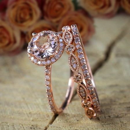 two rose gold wedding rings with an oval cut diamond in the center and side stones on each band