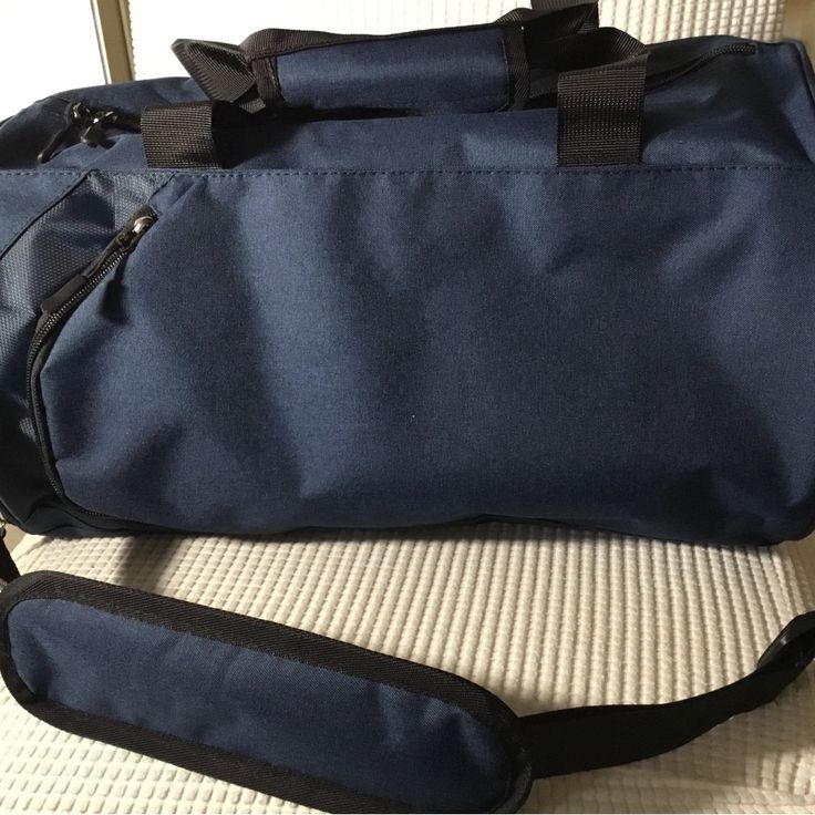 a large blue duffel bag sitting on top of a white couch next to a black strap