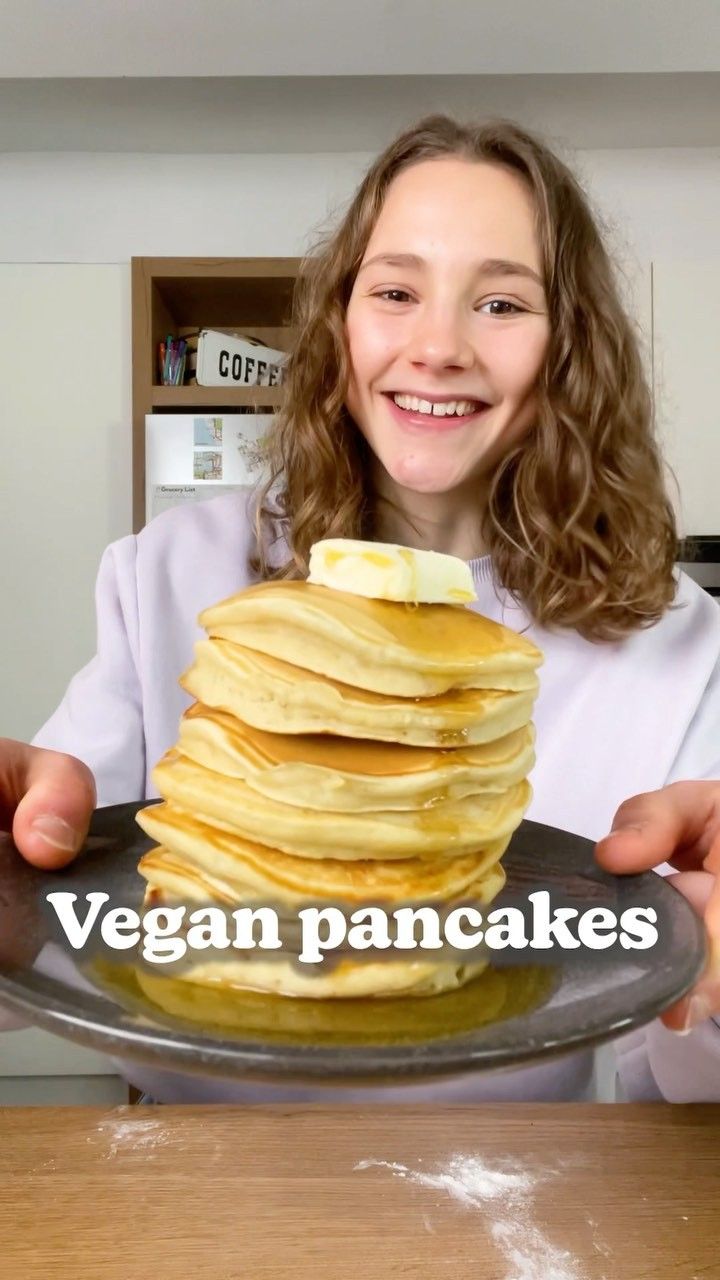 a girl holding a plate with pancakes on it and the caption vegan pancakes