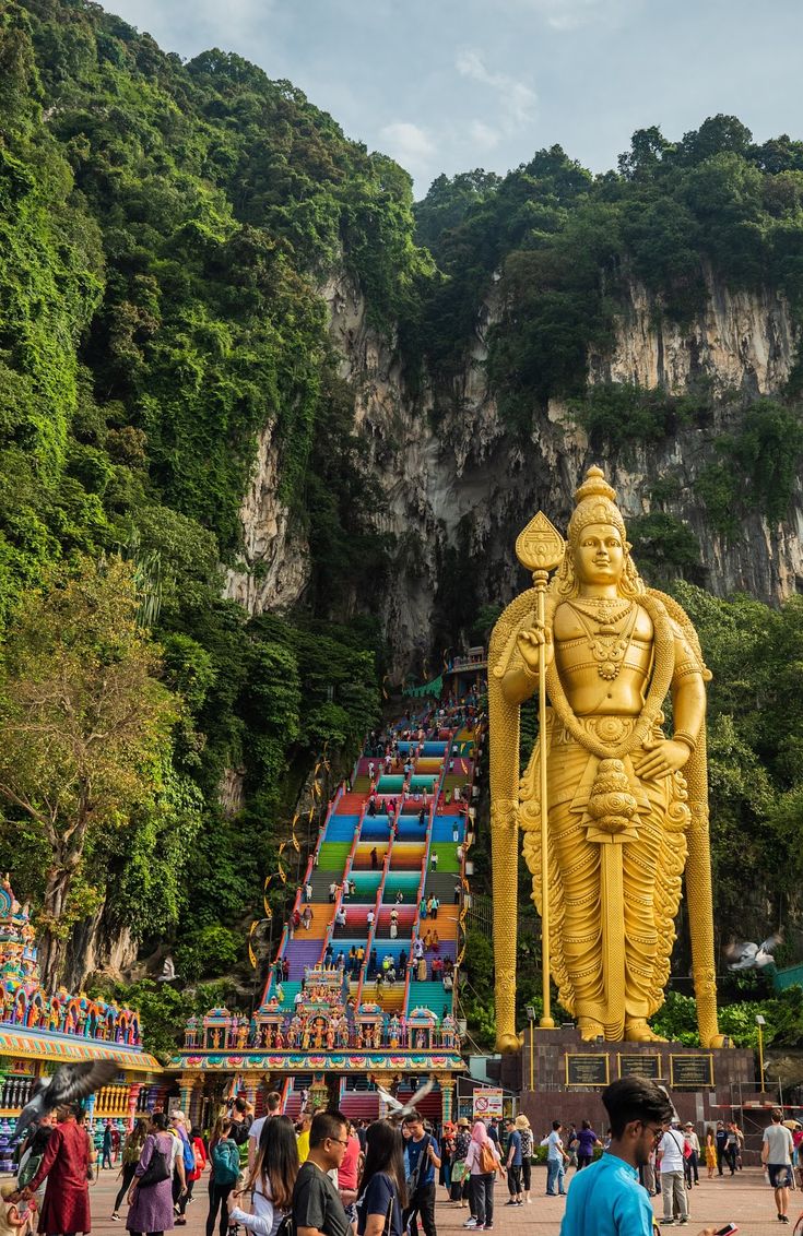 many people are walking around in front of a large statue that looks like a god