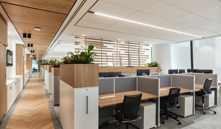 an empty office cubicle with desks and plants on the wall, along with two planters