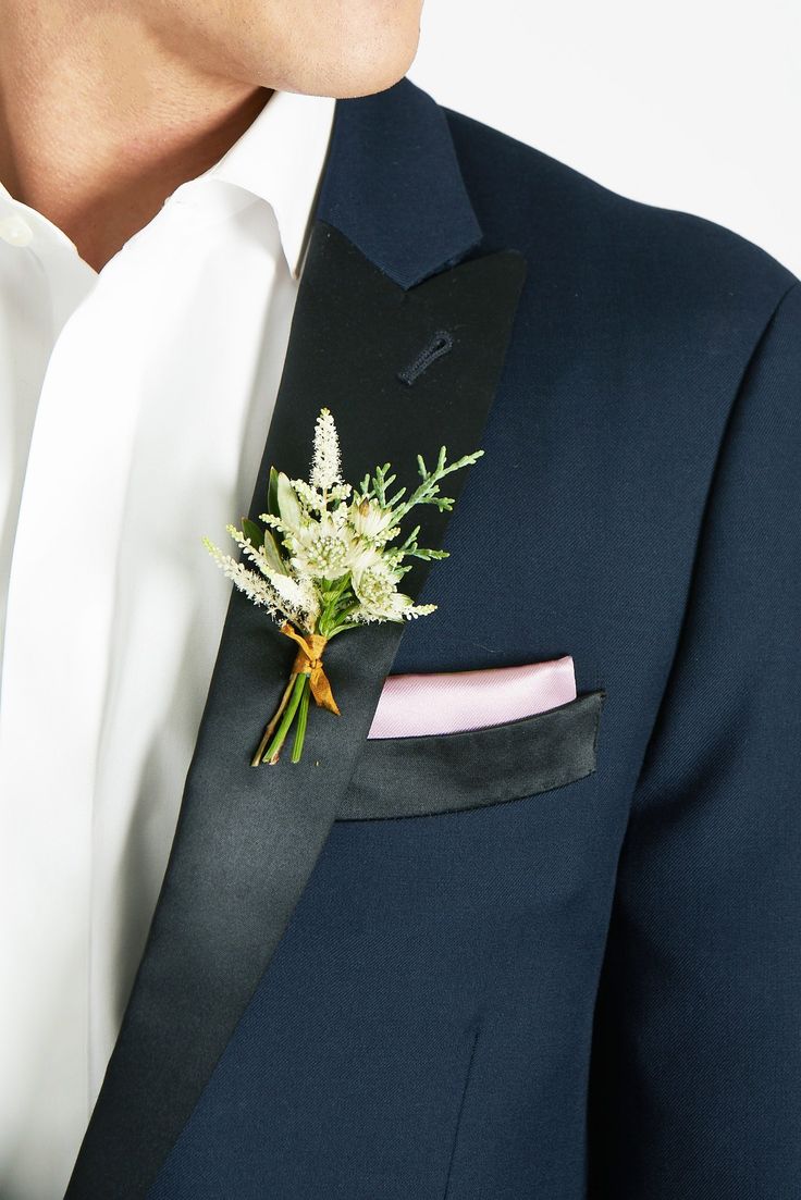 a man wearing a suit and tie with a boutonniere on his lapel