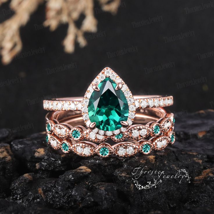 an emerald colored ring set on top of a rock with white and green diamonds around it