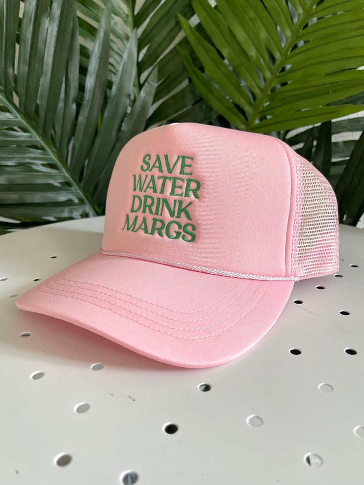 This is a one size fits most trucker hat. The back is mesh and breathable and it has an adjustable backing. It is a solid light pink color with green embroidery that says "save water drink margs". Fabric is 100% Polyester. Spring Breathable Trucker Hat, One Size, Spring Breathable Trucker Hat One Size, Spring Breathable Trucker Hat Visor, Spring Breathable Trucker Hat With Visor, Spring Breathable Visor Trucker Hat, Breathable Visor Trucker Hat For Spring, Pink Trucker Hat With Curved Bill For Outdoor, Pink Trucker Hat For Outdoor, Pink Snapback Hat For Spring Outdoor