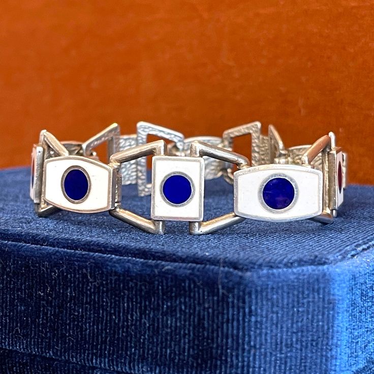 Embark on a journey through time, as we unveil a magnificent treasure that encapsulates the essence of mid-century elegance--a captivating silver bracelet adorned with a bold pattern of blue and white enamel links. Crafted by the renowned Italian jewelry designer Uno A Erre, this exquisite piece invites you to immerse yourself in its timeless allure, where contemporary design intertwines with the vibrant spirit of the era. With its origins in mid-century Italy, this remarkable piece carries with it a sense of cultural richness and artistic heritage. It transcends mere accessory status, becoming a wearable work of art! The bracelet is 7.5 inches long and 18.6 mm north to south, it weighs 36.9 grams. The marks are '1 AR', '925' for sterling silver, and 'Uno A Erre'. Indulge in the captivatin Timeless Blue Round Bracelets, Art Deco Hallmarked Enamel Jewelry, Elegant White Gold Enamel Bracelets, Classic Blue Enamel Jewelry, Art Deco Enamel Jewelry For Formal Occasions, Modernist Jubilee Bracelet For Formal Occasions, Luxury Silver Enamel Bracelets, Modernist Bangle Jewelry Gift, Modernist Bangle Jewelry As Gift