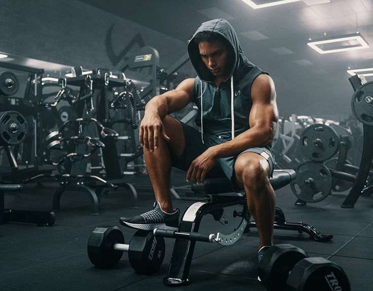 a man sitting on top of a bench in a gym