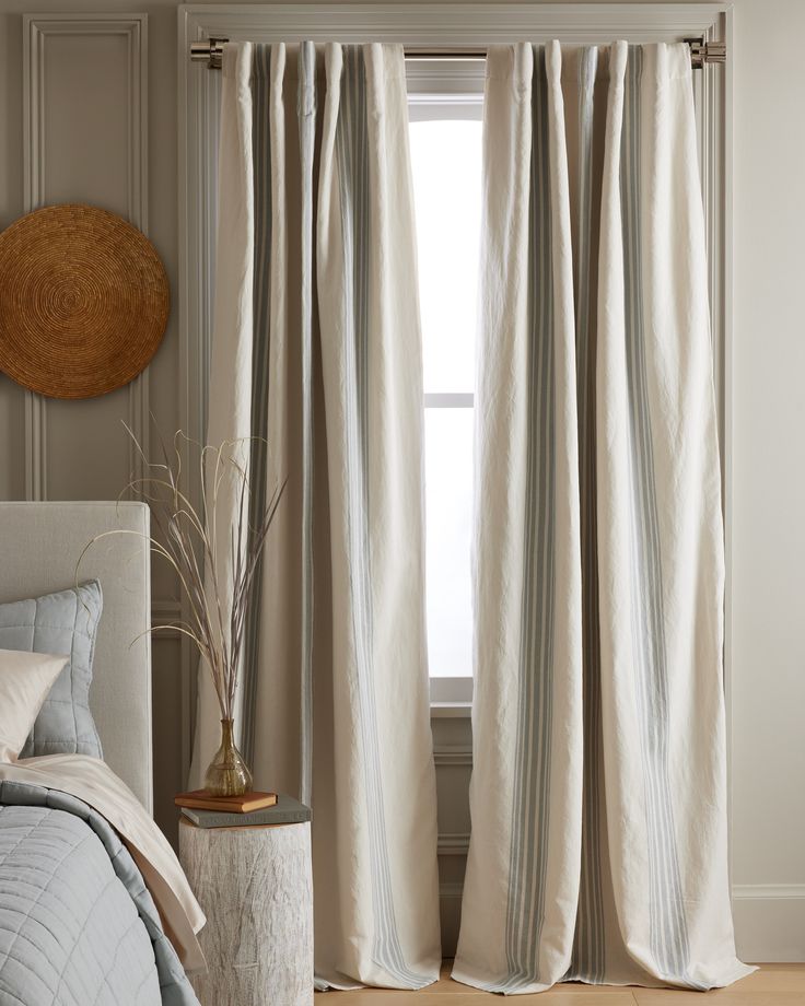 a bed room with a neatly made bed and curtains