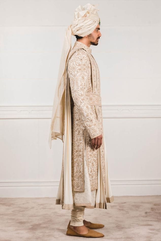 Ivory sherwani with all-over aari zardozi work paired with flared long kurta and churidar. Comes with safa, stole , kamarbandh and jutti fabric.
Components:7
Embroidered
Neckline:Mandarin Collar
Sleeve Length:Sherwani: Full
Fabric:Katan silk, Matka silk, Chanderi
Color:White
Side slits
Closure: Sherwani: Concealed front placket
Note: Brooch on the safa is not for sale - Aza Fashions Wedding Sherwani With Chikankari Embroidery In Traditional Fit, Embroidered Traditional Fit Sherwani For Wedding, Traditional Cream Dupatta With Naqshi, Traditional Cream Dupatta With Naqshi Detail, Cream Dupatta With Naqshi In Traditional Drape, Beige Naqshi Traditional Wedding Wear, Beige Naqshi Traditional Wear For Wedding, White Dabka Sherwani Traditional Fit, White Jamawar Bandhgala With Dupatta