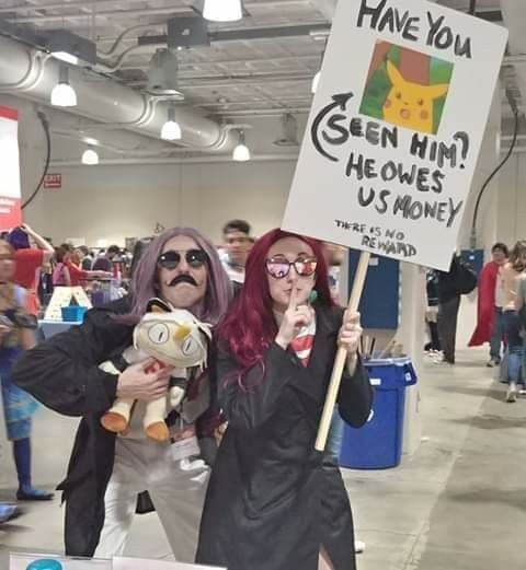 two people dressed in costumes holding signs and posing for the camera