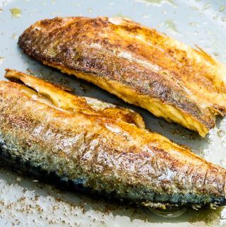 two cooked fish sitting on top of a pan