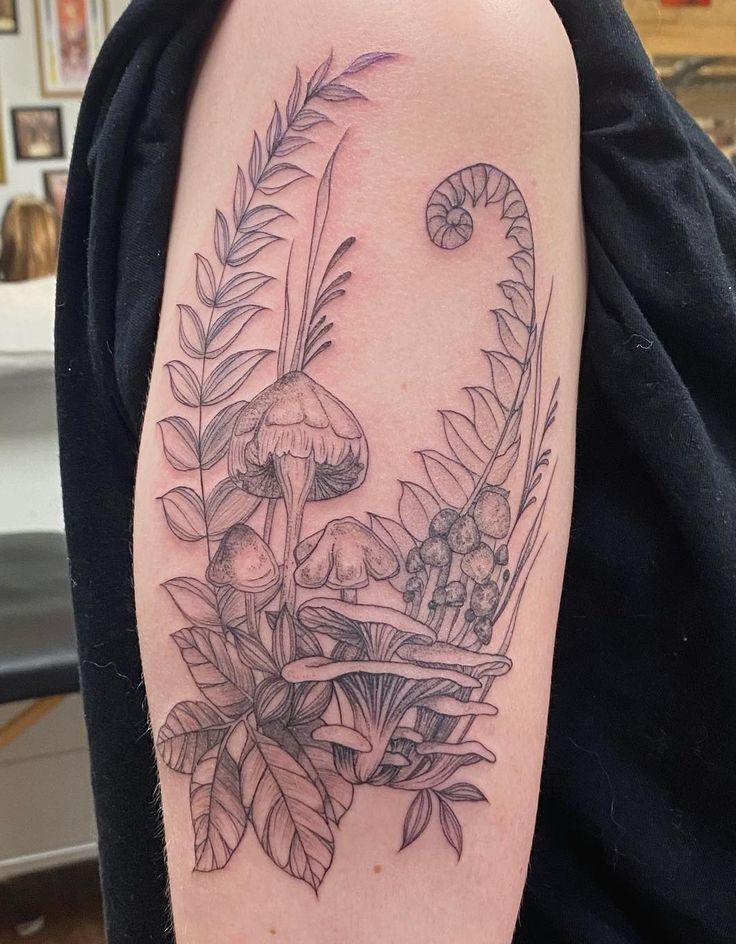 a woman's arm with mushrooms and leaves tattoo on the left side of her body