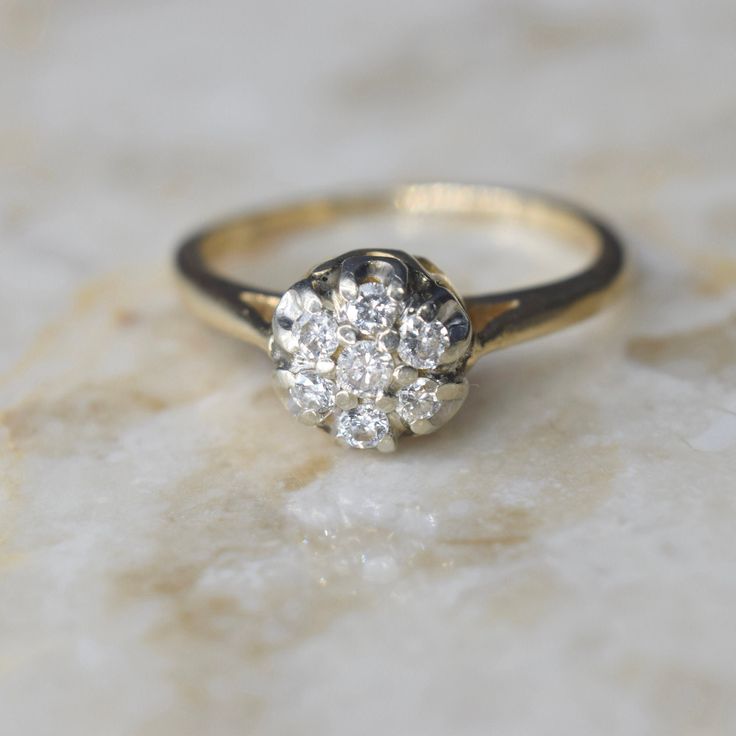 Vintage mid-century diamond cluster ring dating to about the 1950s. It has a raised design for a high-impact look. Each stone is about .05 ct for a ctw of .35 ct.  Era: c.1950s Markings: 14k, Makers mark (W in a diamond frame) Ring Size: 6.5 (your order comes with one free resizing by our jeweler) Condition: Excellent antique condition with minor surface wear from age  Shipping is free in the United States Follow on Instagram @LUXXORVintage Mid Century Ring, Vintage Diamond Cluster Ring With Diamond Cut, Vintage Diamond White Cluster Ring With Diamond Cut, Classic Cluster Promise Ring, Antique Brilliant Cut Diamond Cluster Ring, Antique Diamond Cluster Ring With Brilliant Cut, Vintage Diamond White Cluster Ring With Round Cut, Vintage Cluster Ring In Diamond White With Round Cut, Vintage Yellow Gold Cluster Ring