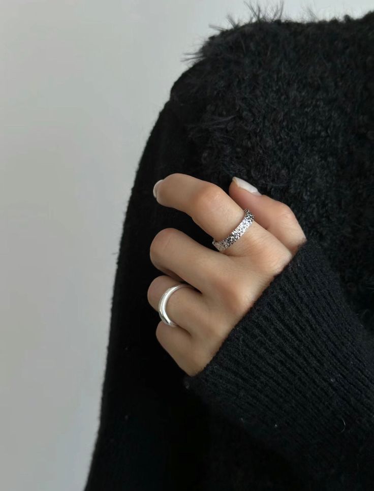 a woman's hand wearing a ring and sweater