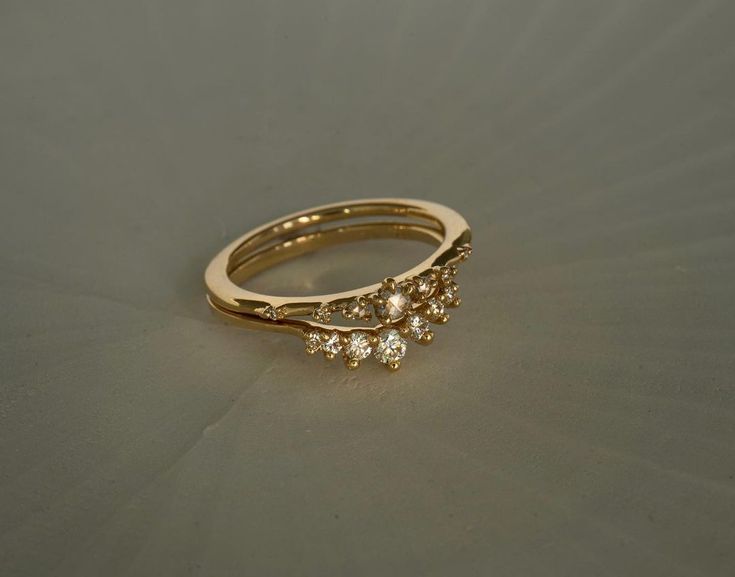 a gold ring with three small diamonds on the top and bottom, sitting on a gray surface