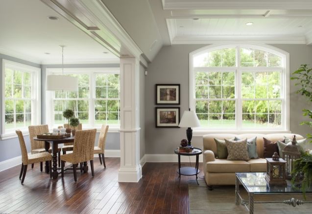 a living room filled with furniture next to a wooden floor covered in lots of windows