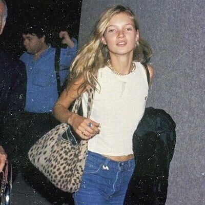 a woman carrying a leopard print purse walking down the street with her hand on her hip