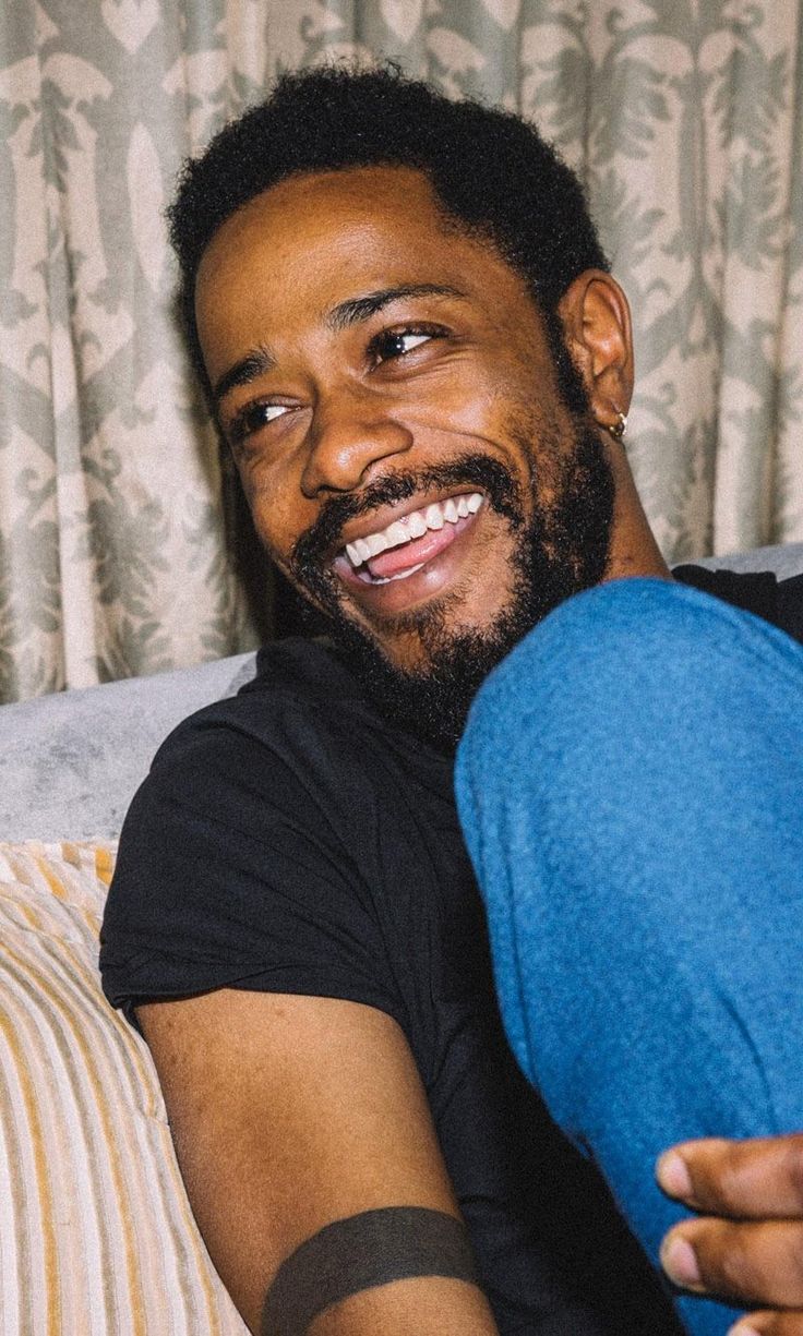 a man laying on top of a couch holding a blue pillow