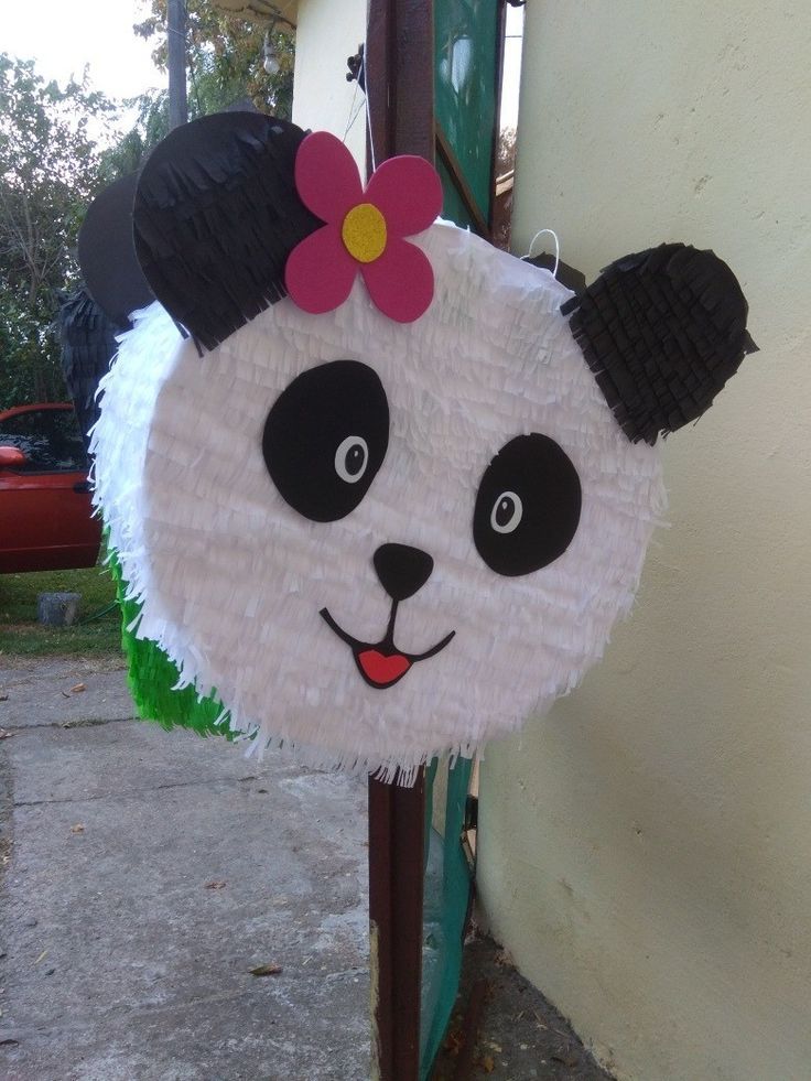 a panda bear pinata hanging on the side of a building with a flower in it's hair