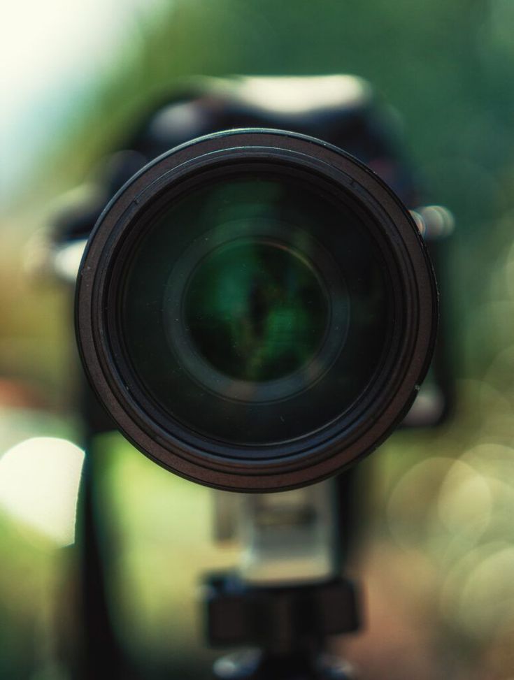 a close up view of a camera lens with blurry trees in the back ground