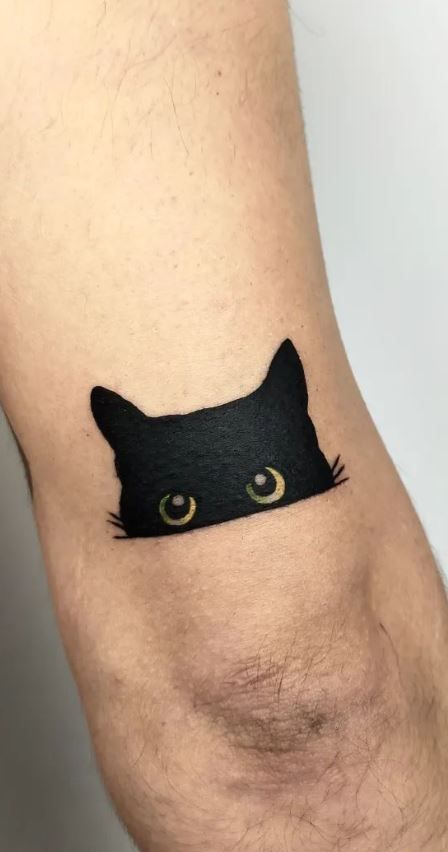 a black cat with yellow eyes on the side of his leg is seen in this tattoo