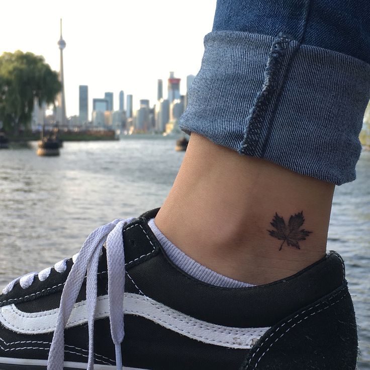 a woman's foot with a small leaf tattoo on her left ankle and the city skyline in the background